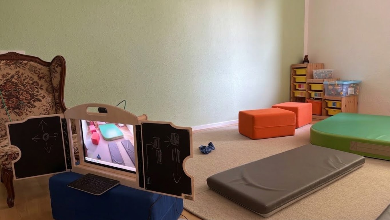 eKami in einem Kitaraum für ein Bewegungsspiel: Auf dem Bildschirm ist die Kameraansicht des Raums zu sehen, an den seitlichen Tafeln sind Bewegungsanweisungen und das Level eingezeichnet.